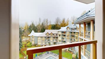 Blick von einem Balkon auf ein Hotel mit mehreren Etagen, einem Schwimmbad und einem angelegten Garten.