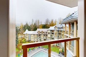 A view from a balcony overlooking a hotel with multiple floors, a swimming pool, and a landscaped garden. - Whistler Cascade Lodge (Whistler)
