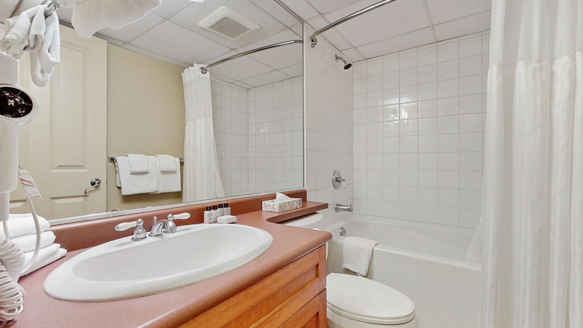 A modern bathroom with a white sink, vanity, and bathtub.