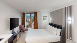 A modern hotel room with a large bed, a flat-screen TV, a desk with a computer, and a chair. - Whistler Cascade Lodge (Whistler)