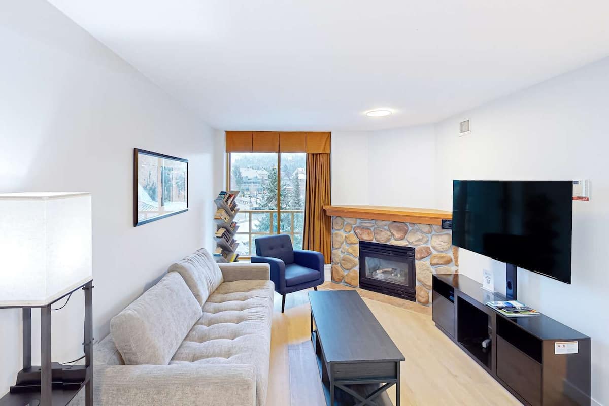 Una sala moderna con un sofá, un sillón azul, una chimenea y un televisor.