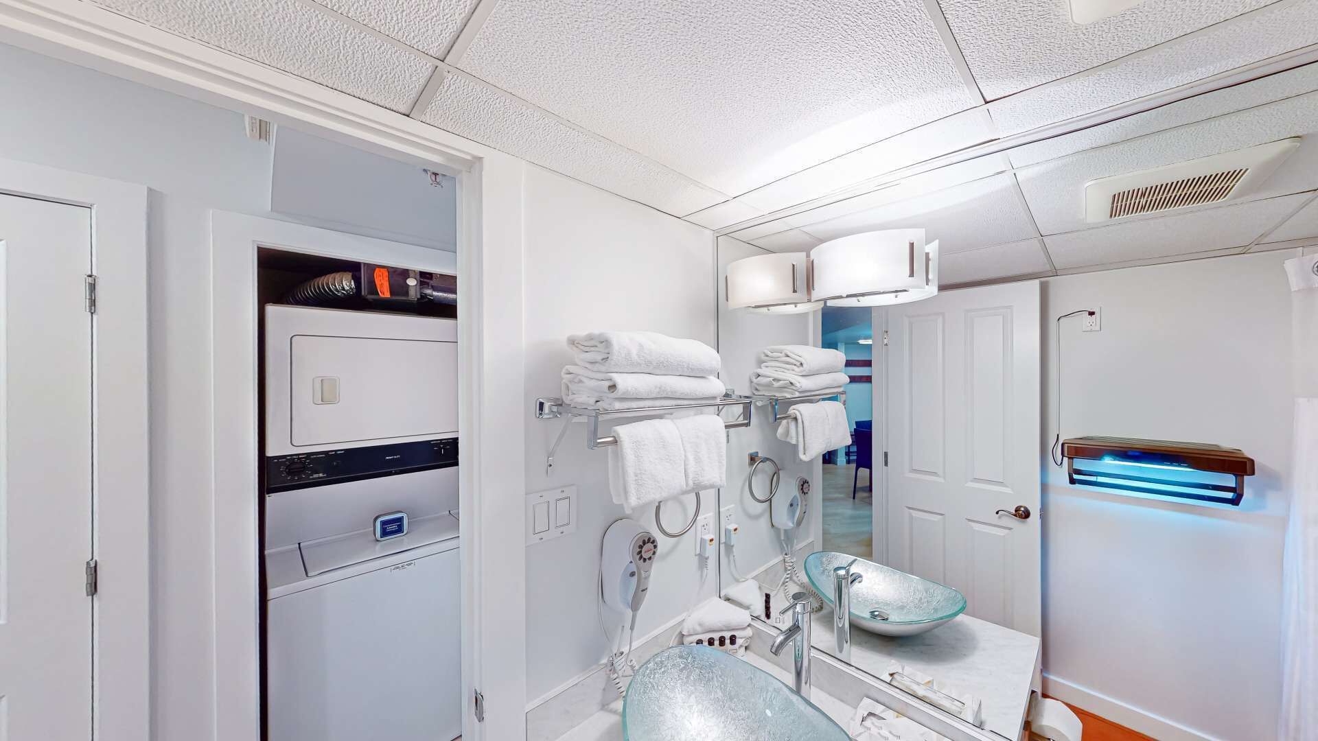 A modern bathroom with a glass sink, towel rack, and a visible hairdryer.