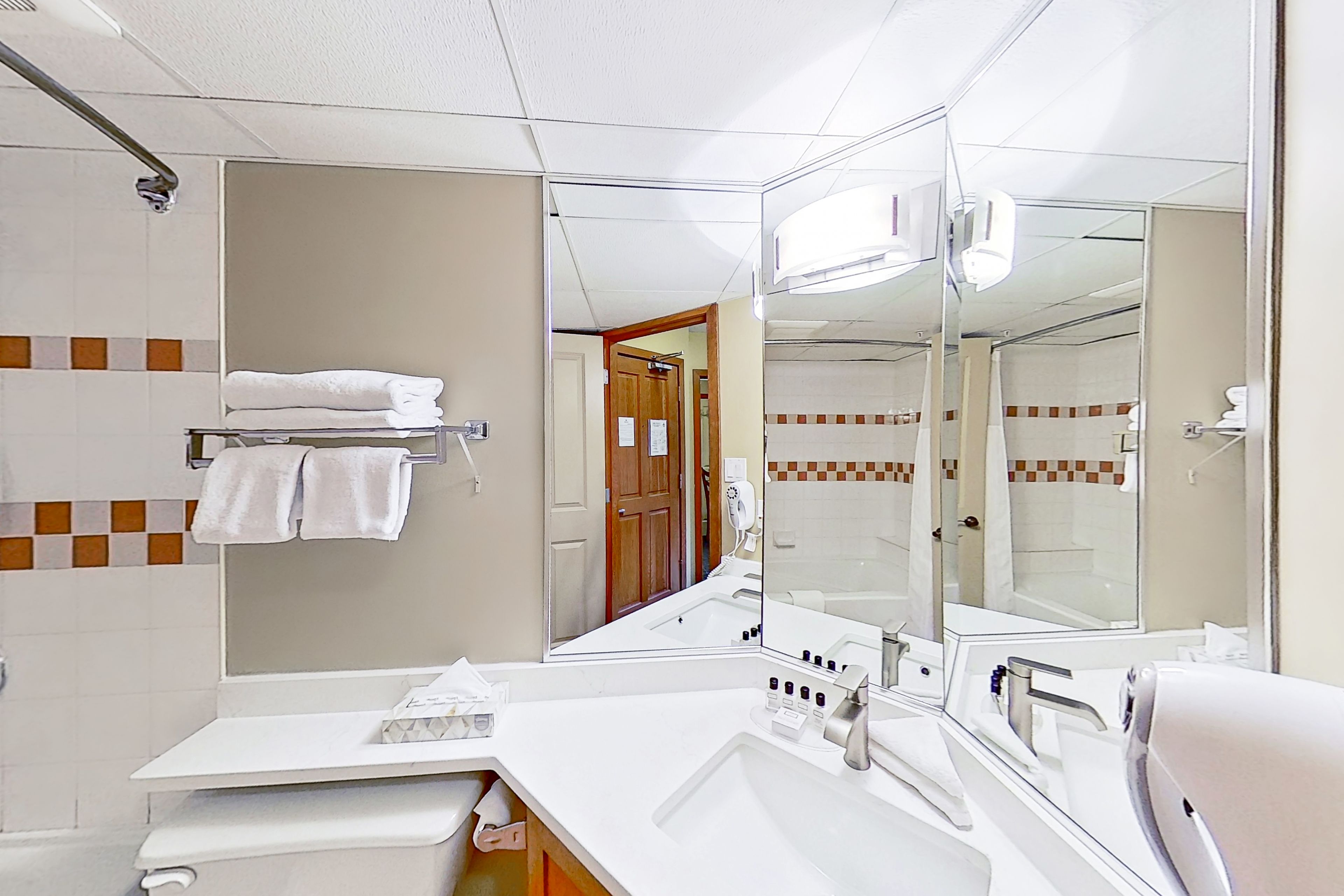 A hotel bathroom with a large mirror, a sink, and a towel rack.