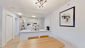 A modern kitchen with white cabinets, a central island, and a dining table with chairs.