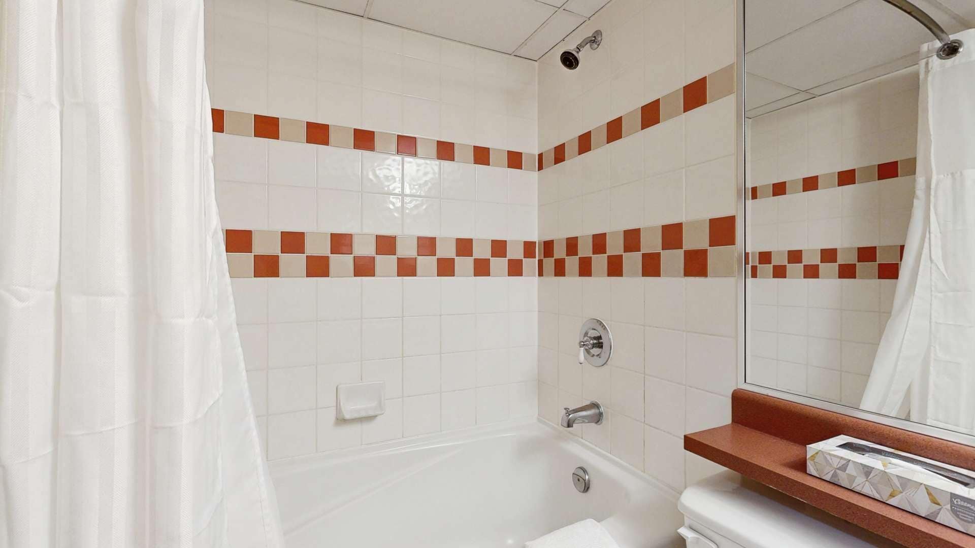 A bathroom with a bathtub, a toilet, a sink, and a mirror.