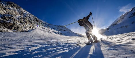 A skier on a snowy slope with a clear sky.