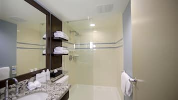 Une salle de bain équipée d’un lavabo, d’un miroir, d’un porte-serviettes et d’une zone douche.