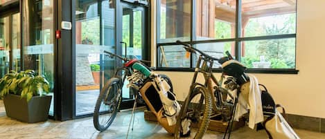 Entrada de un edificio con puertas de vidrio, una bicicleta y una maceta.