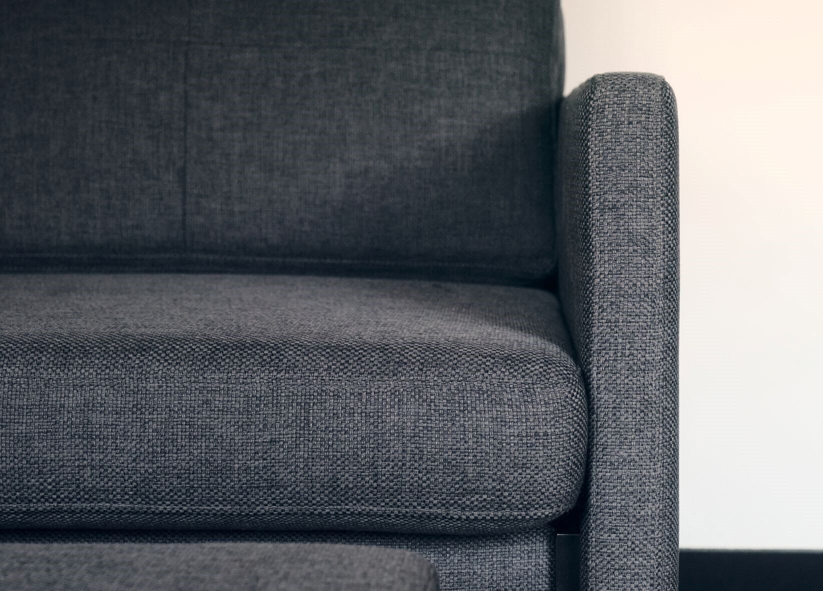 A close-up of a grey upholstered sofa with a textured fabric.