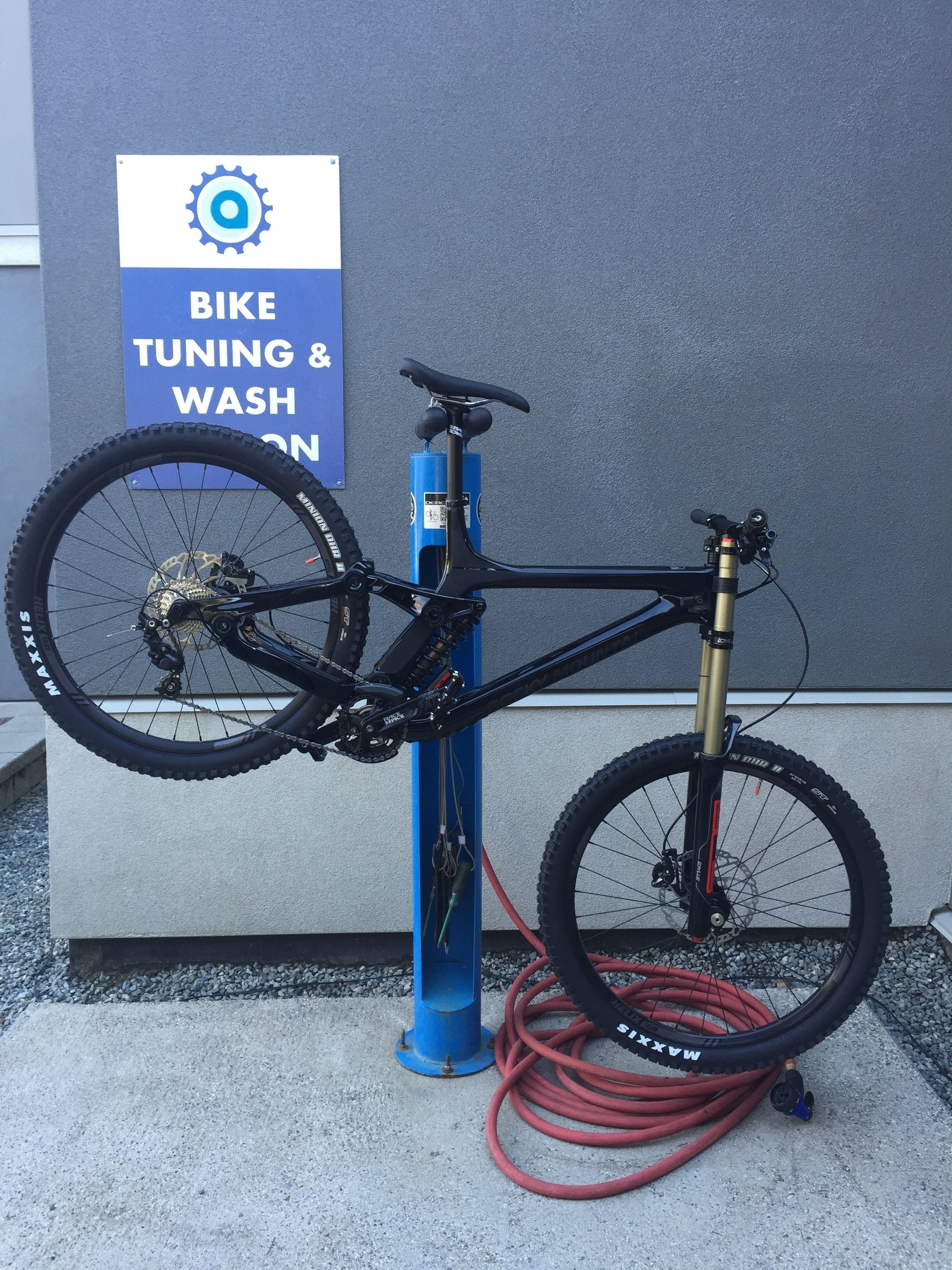 A bicycle parked next to a sign that reads "BIKE TUNING & WASH ON".
