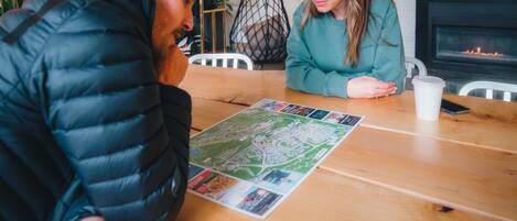Dos personas sentadas en una mesa de madera con un mapa, una taza blanca y un teléfono inteligente.