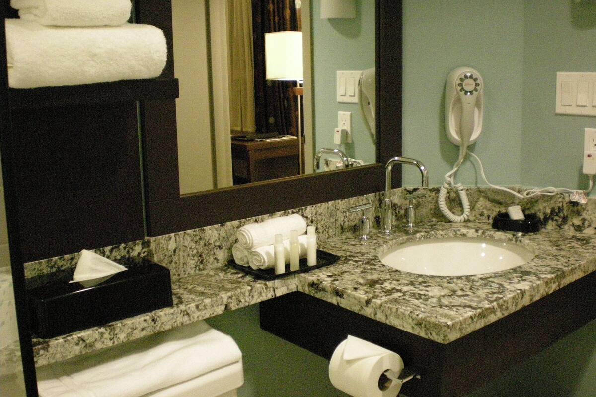 Un baño con lavabo, espejo, toallero y secador de pelo.