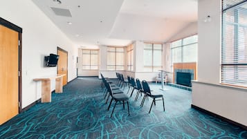 Un salón de conferencias con una larga mesa, sillas y una televisión.