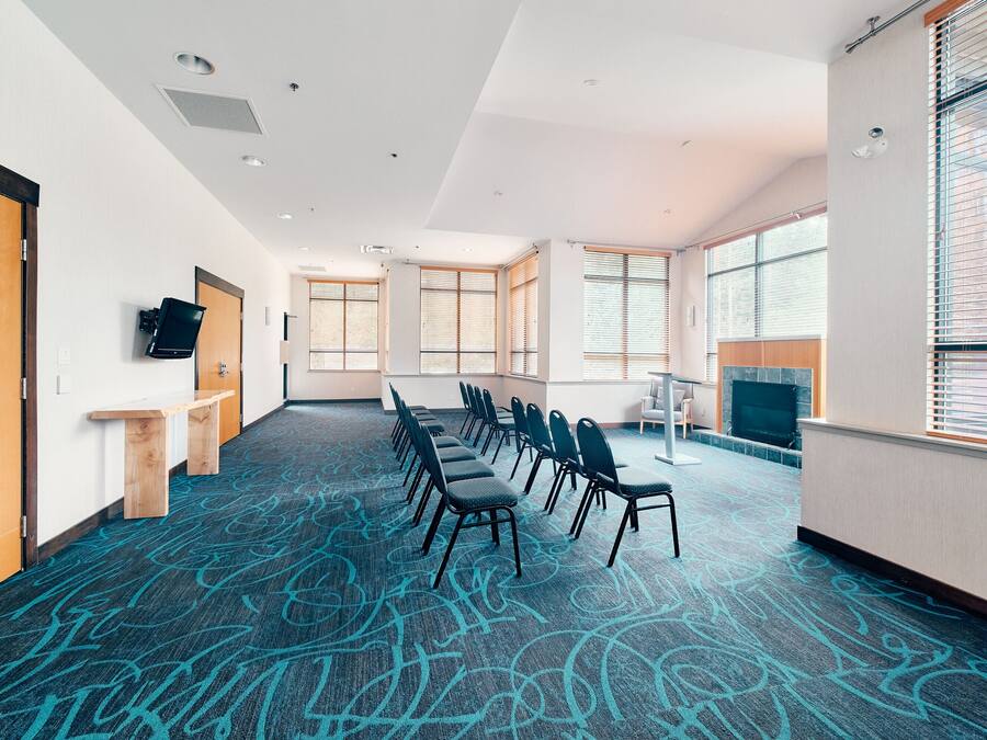Un salón de conferencias con una larga mesa, sillas y una televisión.