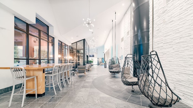 A modern interior with a long bar area, seating, and hanging chairs.