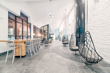 A modern interior with a long bar area, seating, and hanging chairs.