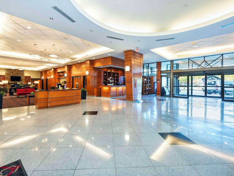 A spacious lobby with a reception desk, seating area, and a large glass entrance.