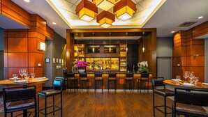 A bar area with wooden paneling, multiple bar stools, and a well-lit ceiling with geometric light fixtures. - Grand Park Hotel Vancouver Airport, an Ascend Collection Hotel (Richmond)