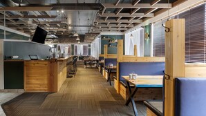 A modern restaurant with wooden furniture, a herringbone floor, and a long counter.