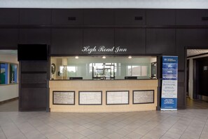 A reception desk at High Road Inn with a modern design, a glass partition, and a digital screen.
