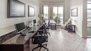 A modern office space with a long desk, multiple chairs, and framed pictures on the walls.