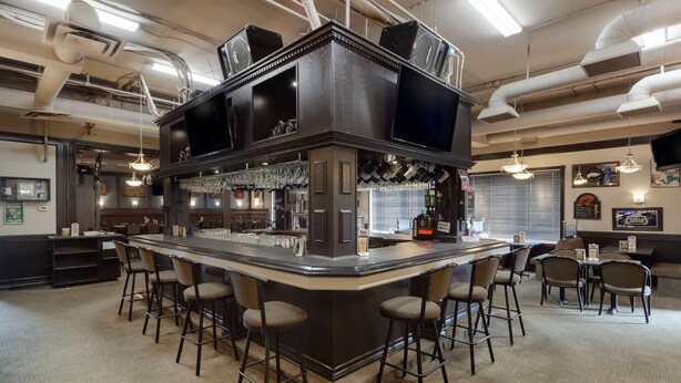 A bar area with a central island, bar stools, and a seating area with tables and chairs.