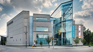 A modern building with a glass facade, a visible sign for the Chingazuk Museum, and a traffic light.