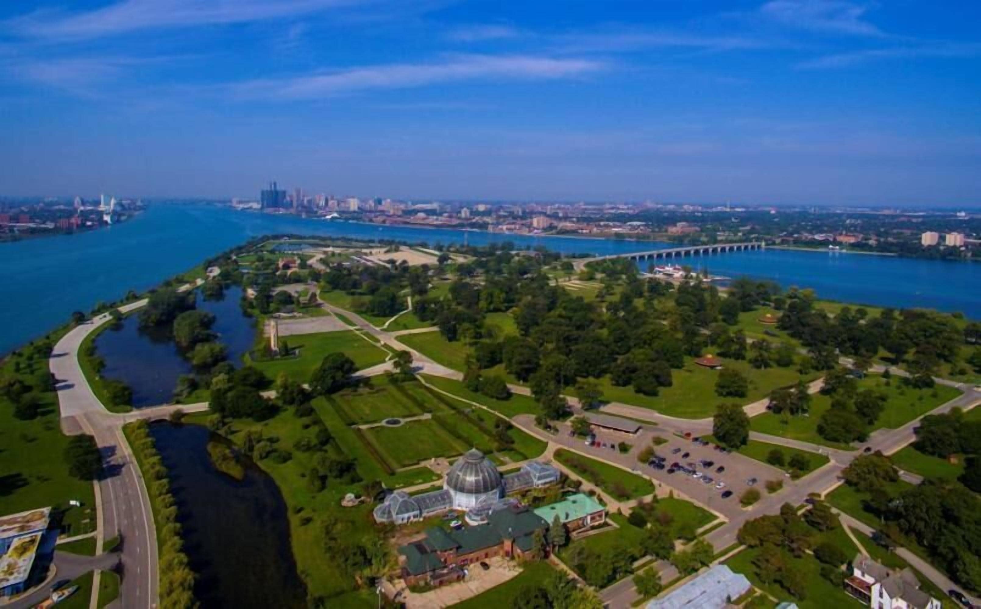 An aerial view of a park with a large dome structure, a bridge, and a river.