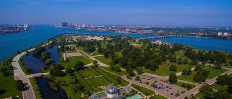 An aerial view of a park with a large dome structure, a bridge, and a river.