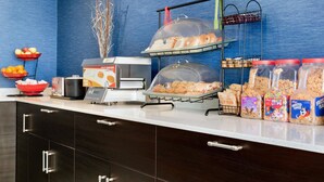 A breakfast bar with various food items, including cereals and bread, and a coffee maker.