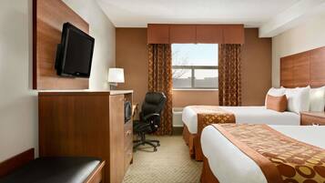 A hotel room with two beds, a desk, a chair, a television, and a window with curtains.