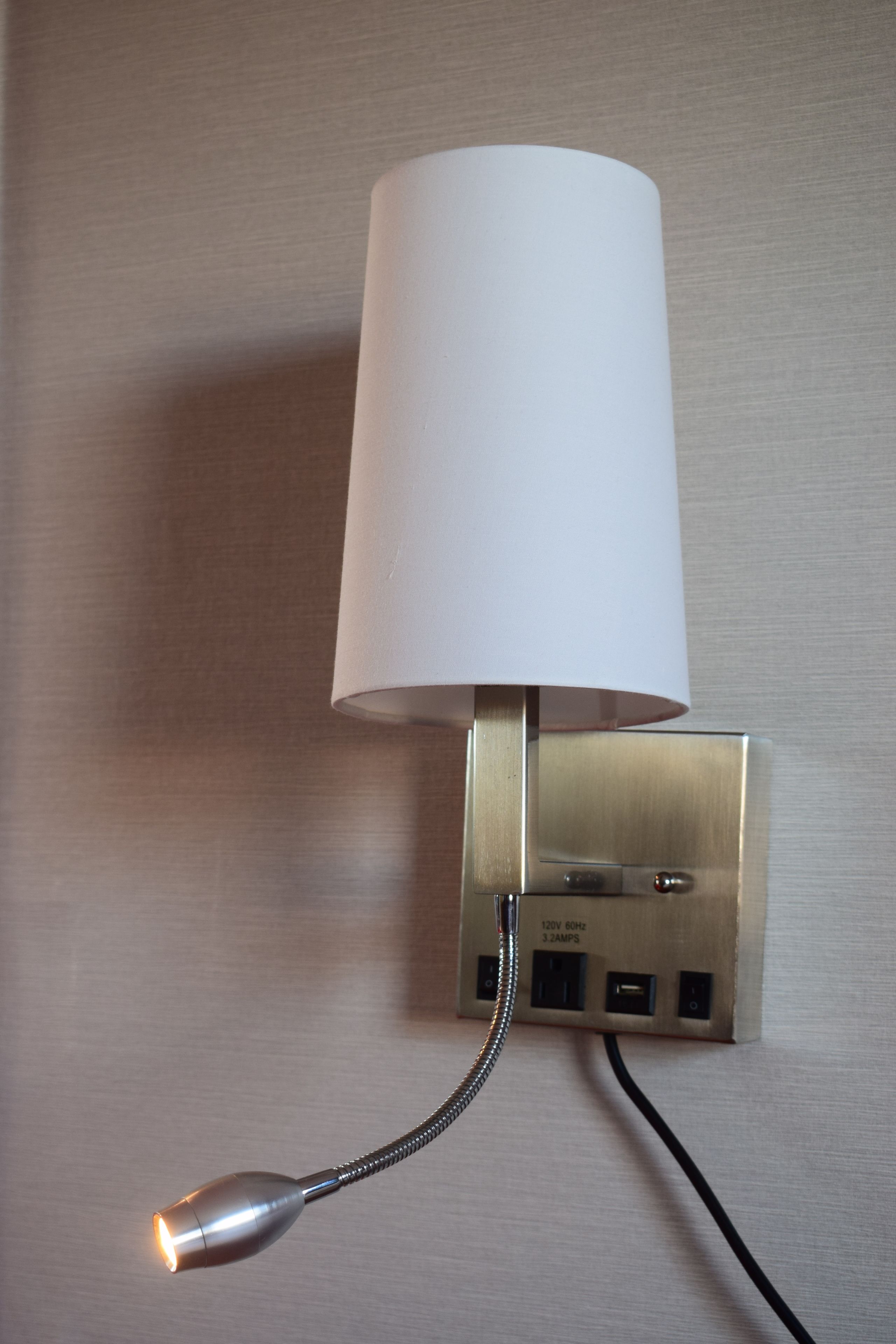 A wall-mounted lamp with a cylindrical shade and a flexible neck.