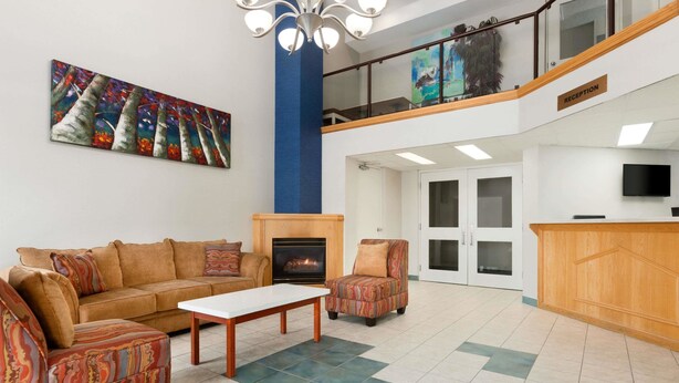 A spacious lobby with a fireplace, a reception desk, and a staircase leading to an upper level.