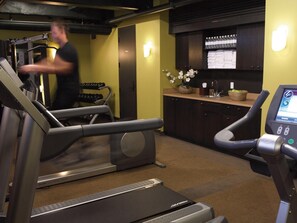 A gym with treadmills, a weight bench, and a digital fitness machine. - Hôtel Le Germain Québec (Québec City)