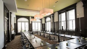 Un salón de conferencias con largas mesas, sillas y ventanas amplias.