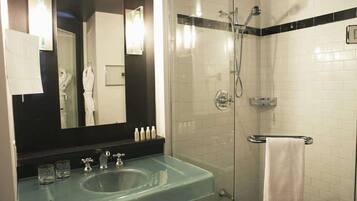 Une salle de bain moderne avec un lavabo en verre, un grand miroir, une douche à parois de verre et un porte-serviettes.