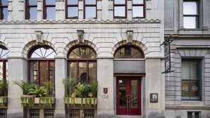 Un edificio histórico con puerta roja, ventanas arqueadas y una placa con el número de la dirección.