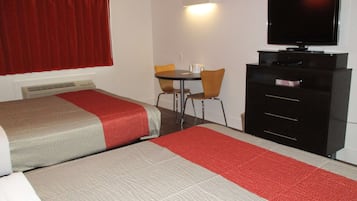 Een hotelkamer met twee bedden, een bureau met stoel, een televisie en een dressoir.