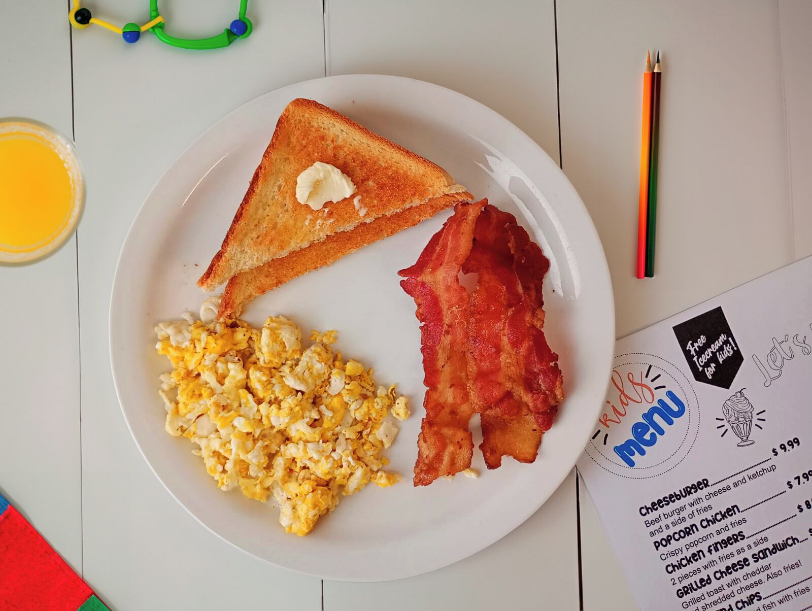 A plate with toast, scrambled eggs, and bacon.