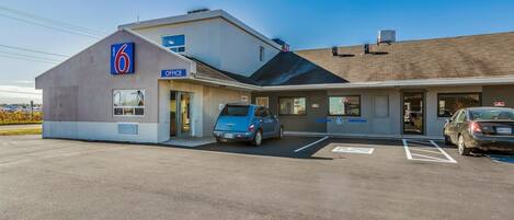 Un motel avec une enseigne indiquant le chiffre « 6 », une autre indiquant « BUREAU » et une troisième réservée aux places de stationnement pour personnes handicapées.