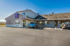 Un motel con un letrero del número '6', un letrero que dice 'OFICINA' y un letrero de estacionamiento para discapacitados.