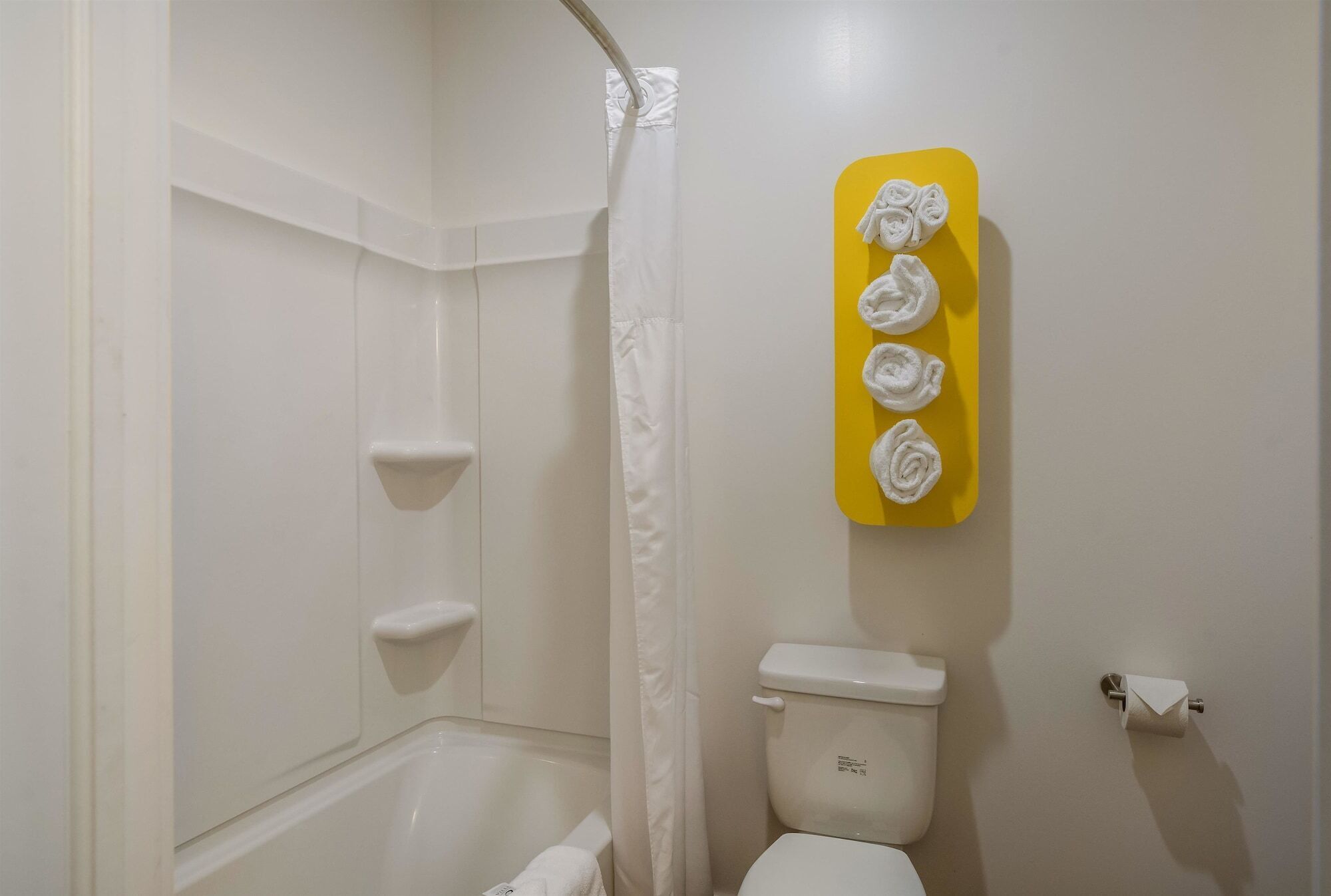 Un baño con bañera, inodoro y un toallero amarillo con toallas.