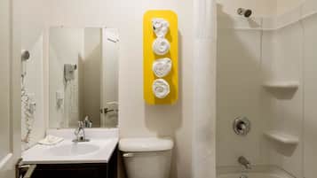 A bathroom with a white sink, toilet, and shower. There is a yellow towel rack with three towels.