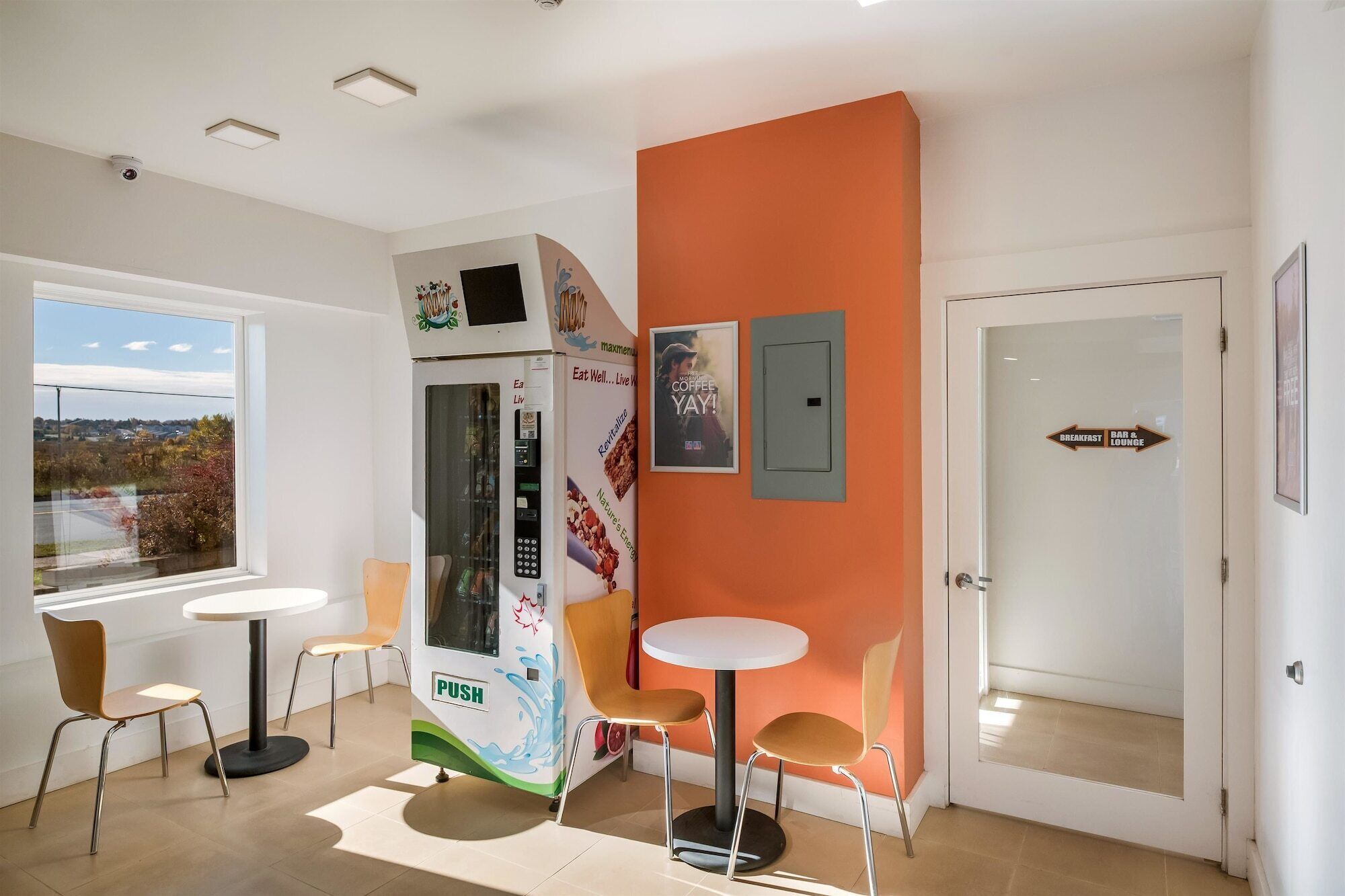 A modern interior with a vending machine, two tables, and chairs.