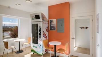 A modern interior with a vending machine, two tables, and chairs.