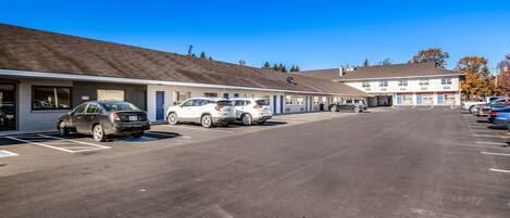 A motel with a parking lot and several cars parked in front.