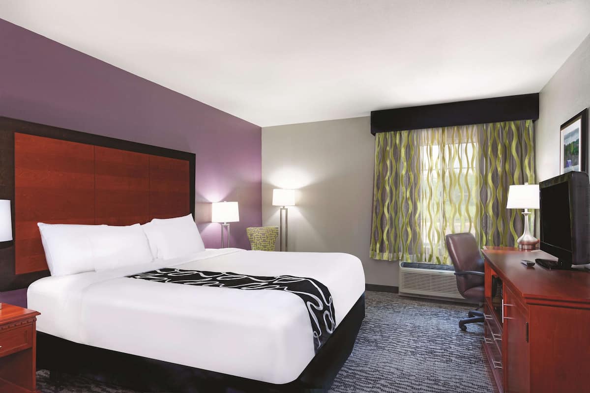 Une chambre d’hôtel avec un grand lit, un bureau équipé d’un ordinateur, une chaise et un téléviseur.
