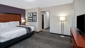 Hotellihuone, jossa on suuri sänky, taulutelevisio, työpöytä ja lamppu.