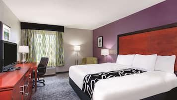 Habitación de hotel con una cama grande, un escritorio con computadora, una silla y dos lámparas.