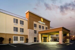 Un hôtel avec une enseigne « La Quinta », une entrée abritée et un parking.